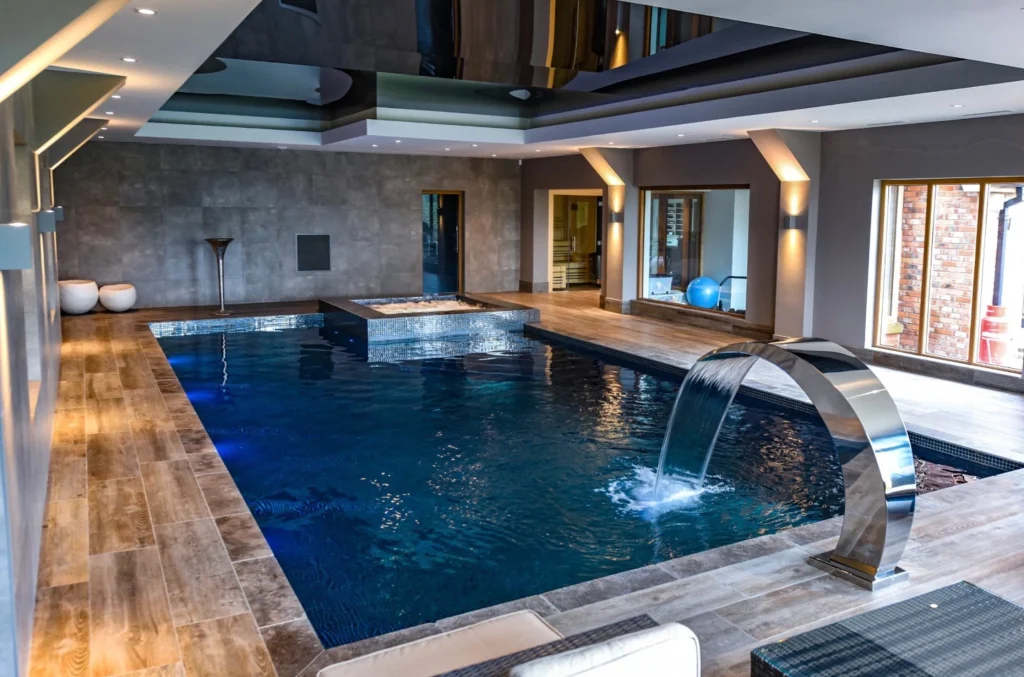 Luxury indoor swimming pool with waterfall feature and modern design