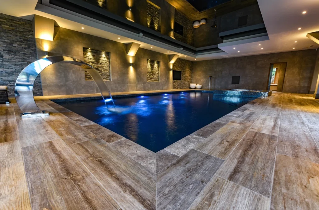 Luxury indoor swimming pool with blue lighting and waterfall feature