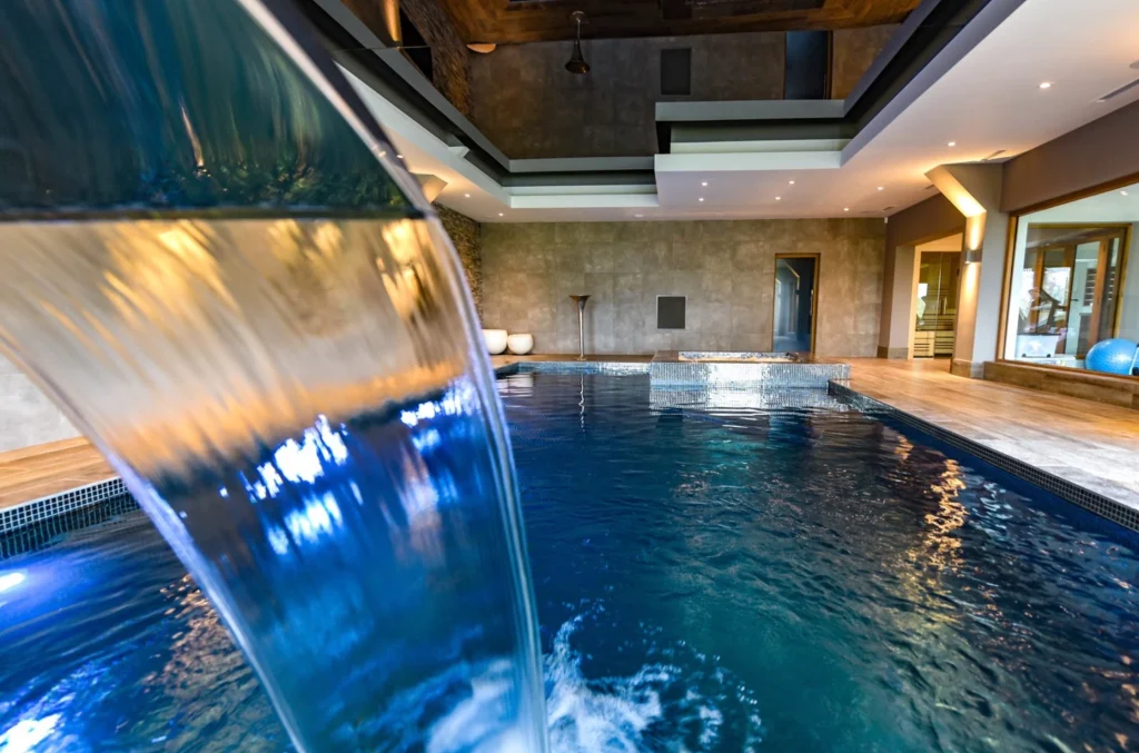 Luxury indoor swimming pool with waterfall feature and modern design