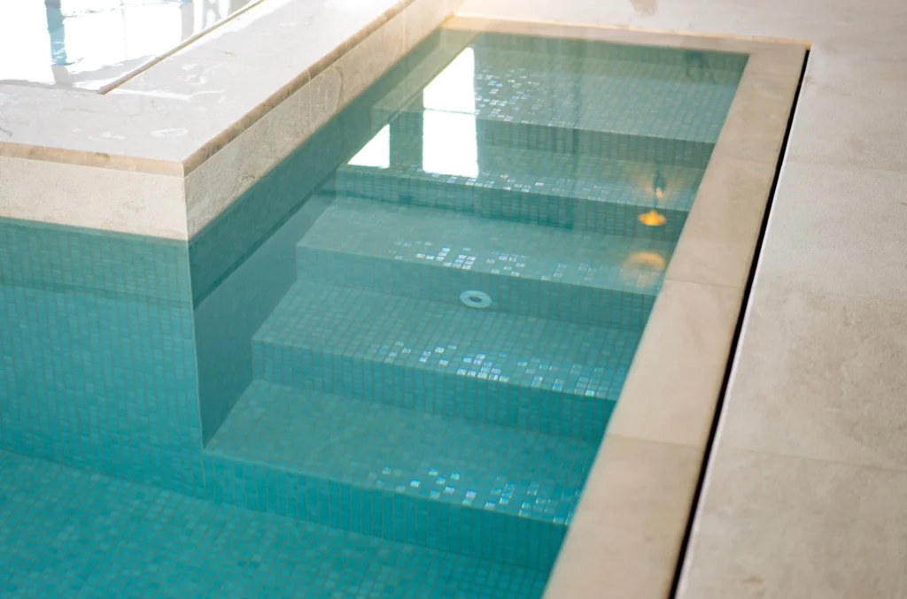 Turquoise tiled swimming pool with integrated spa jets