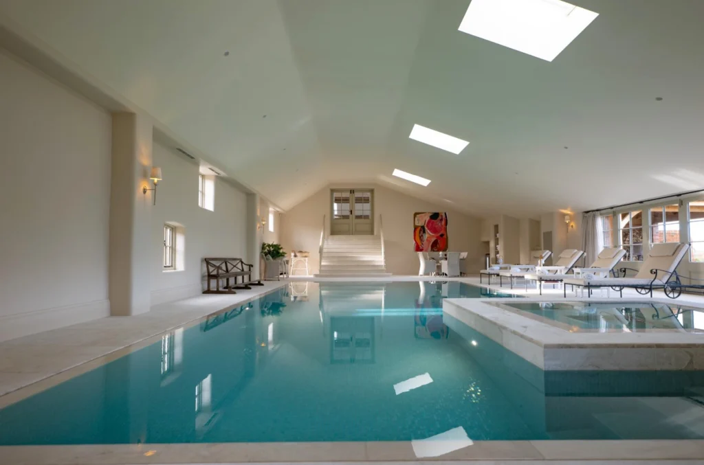 Luxurious indoor swimming pool with natural light and lounge chairs