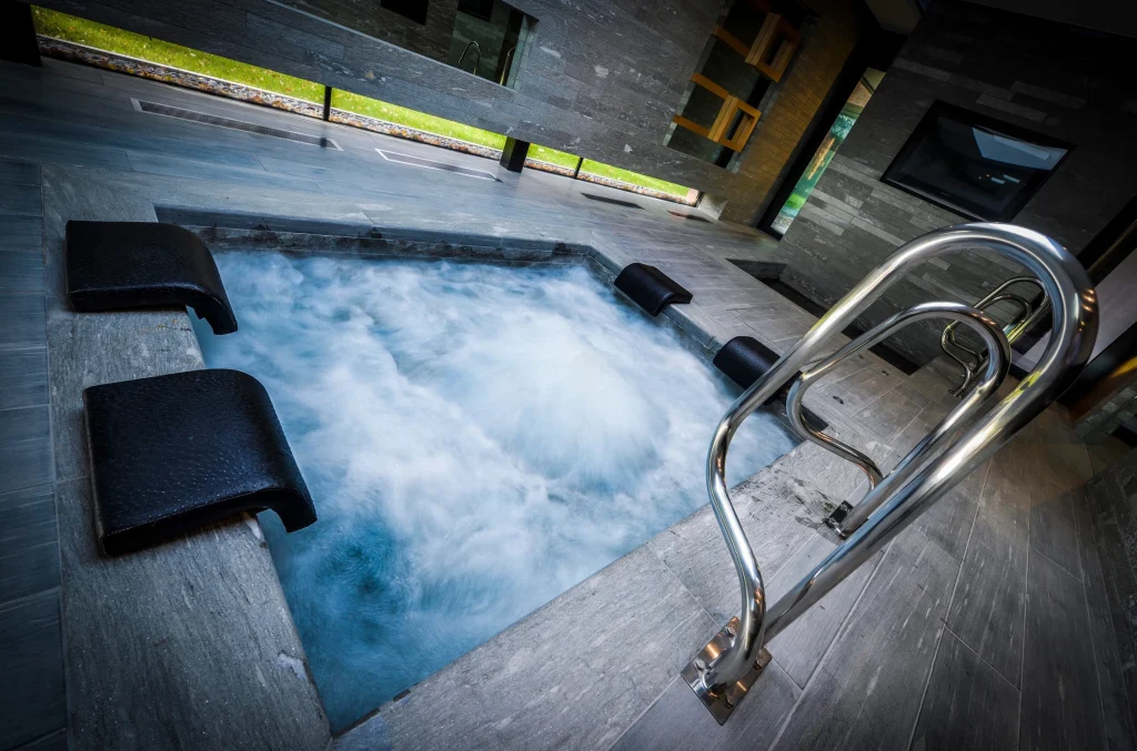 Steaming hot tub with bubbling water and handrails indoors