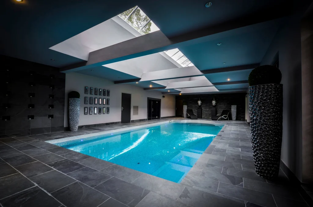 Modern indoor swimming pool with skylights and teal ceiling