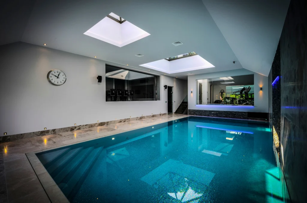 Modern indoor swimming pool with skylight and gym room