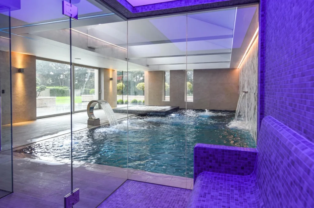 Luxury indoor swimming pool with purple lighting and glass enclosure