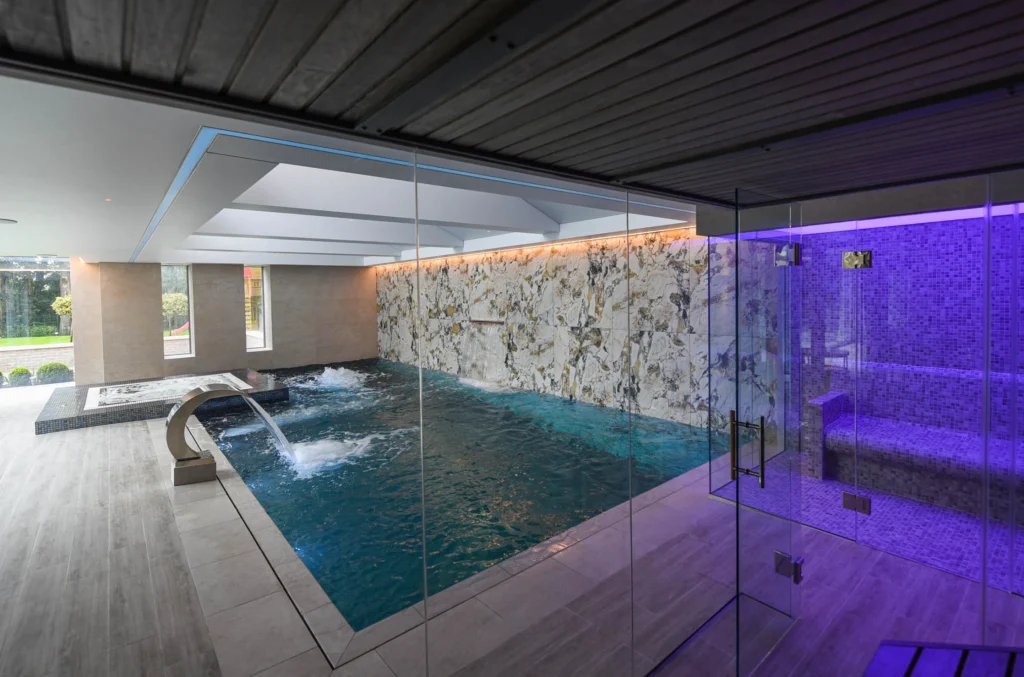 Modern indoor swimming pool with purple lighting and spa area