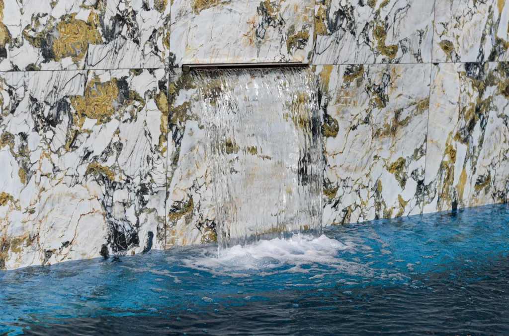Water cascading from metal chute into turquoise sea below