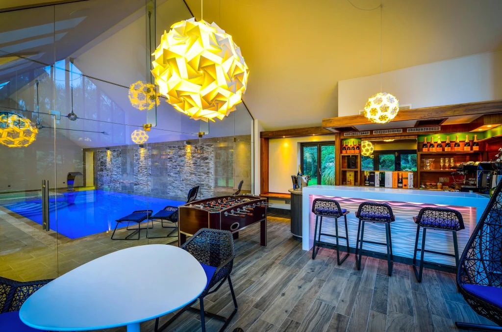 Modern leisure facility with pool, bar, and geometric pendant lights