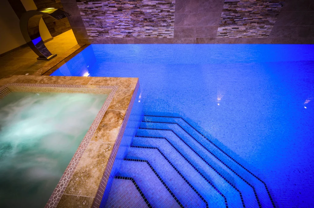 Indoor swimming pool with blue LED lighting and steps
