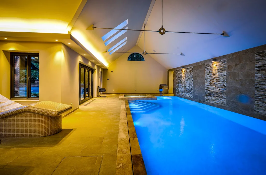 Luxury indoor swimming pool with illuminated blue water and yellow lighting
