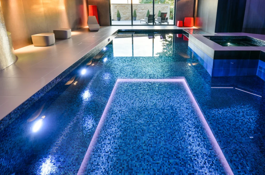 Luxury indoor swimming pool with blue mosaic tiles and lighting