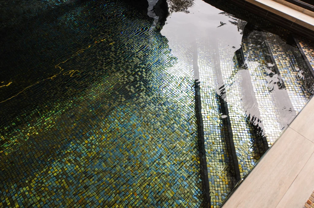 Swimming pool with blue and yellow mosaic tiles and water reflection