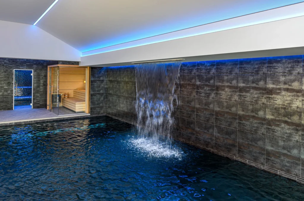 Modern indoor swimming pool with waterfall and sauna