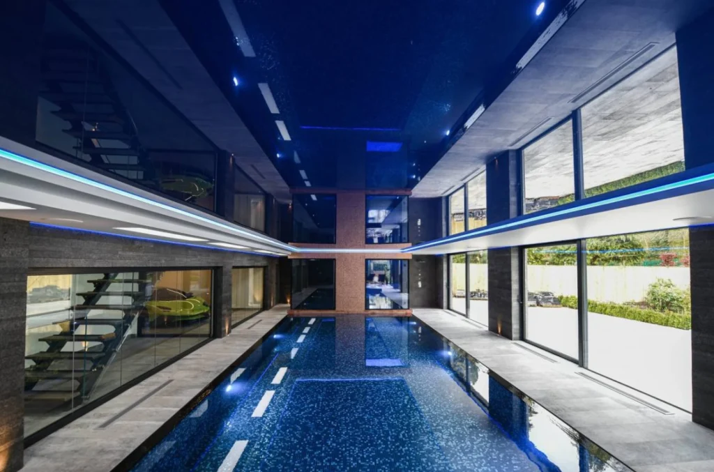 Modern indoor swimming pool with blue LED lighting and glass walls
