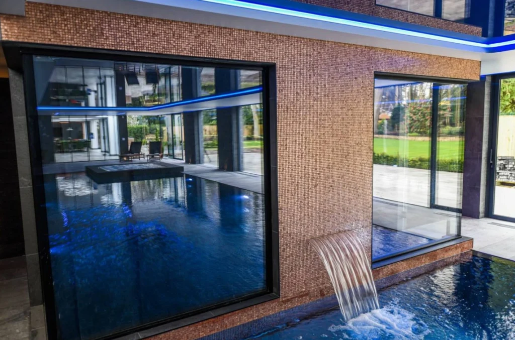Modern indoor swimming pool with brick walls and blue lighting