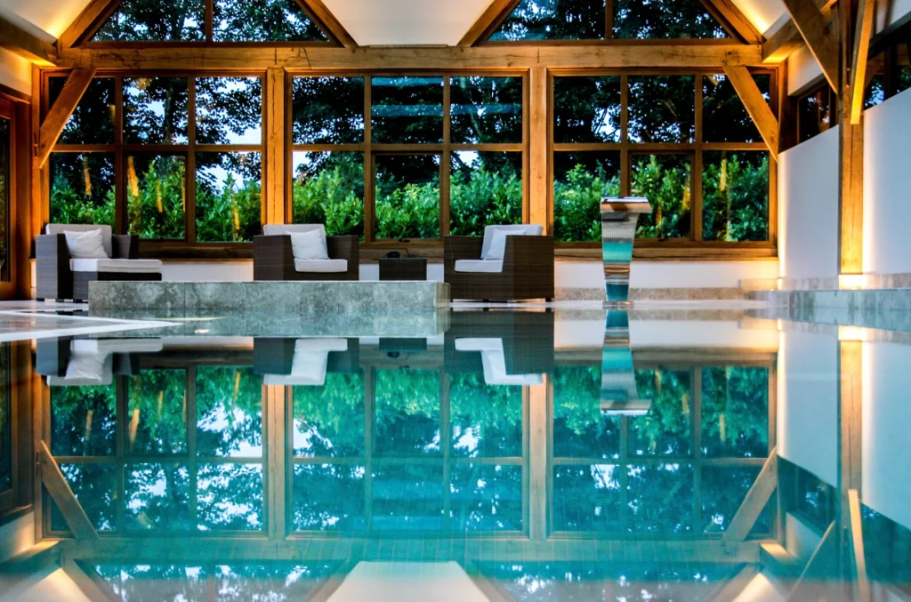 Luxury indoor swimming pool with wooden beams and forest views