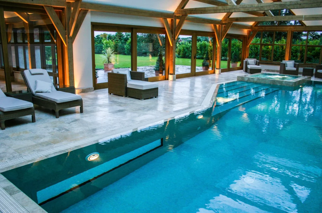 Luxury indoor swimming pool with lounge chairs and garden views