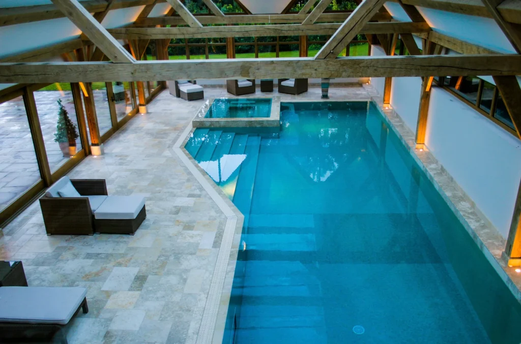 Indoor swimming pool with wooden beams and loungers