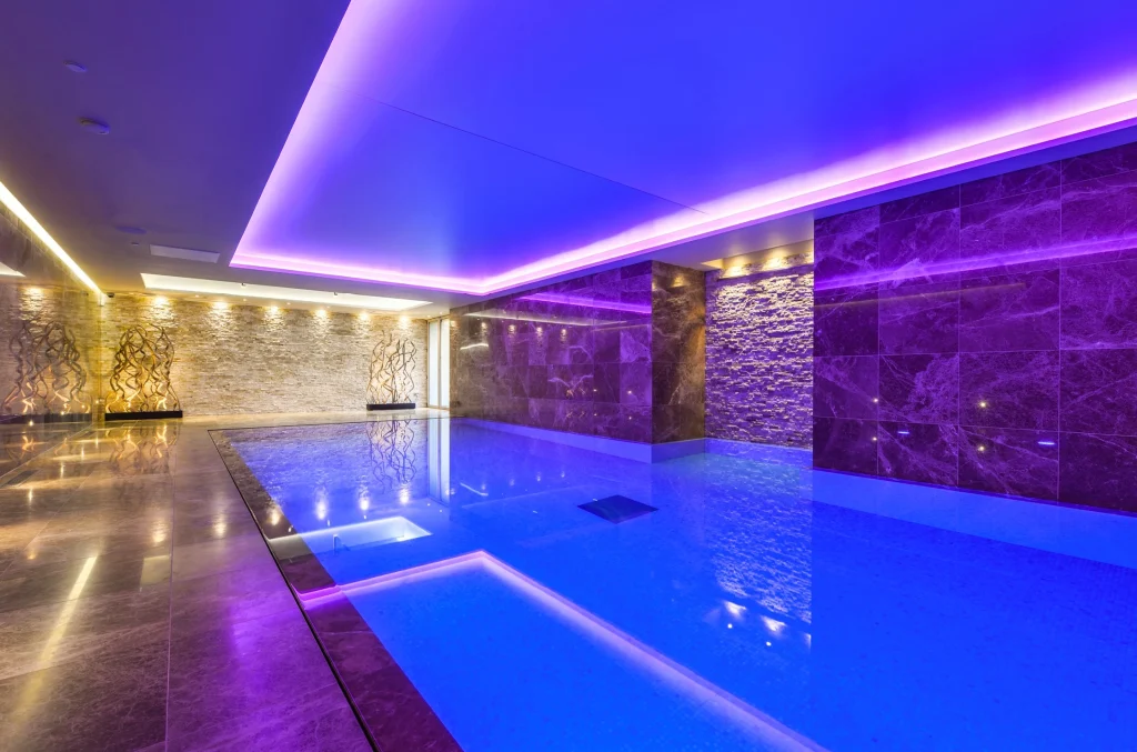 Luxury indoor swimming pool with vibrant purple neon lighting