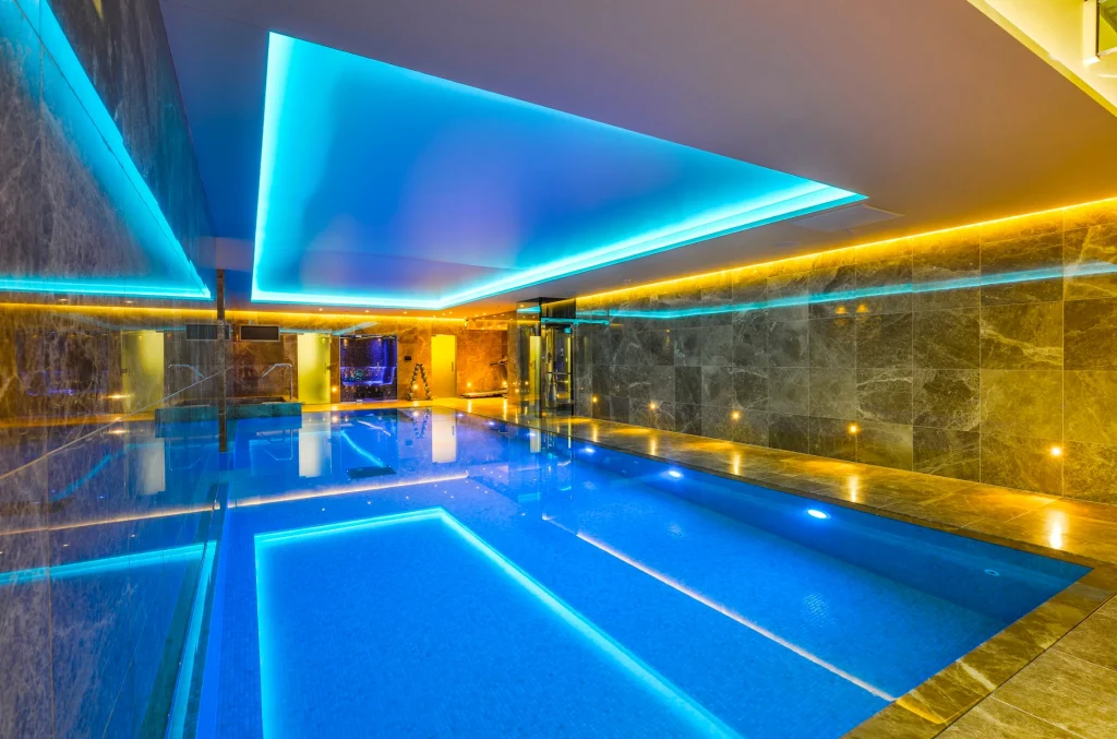 Modern indoor swimming pool with cyan and gold neon lighting
