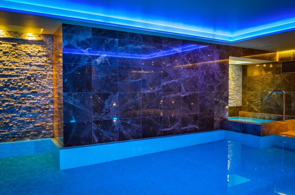 Luxury indoor swimming pool with blue lighting and marble walls