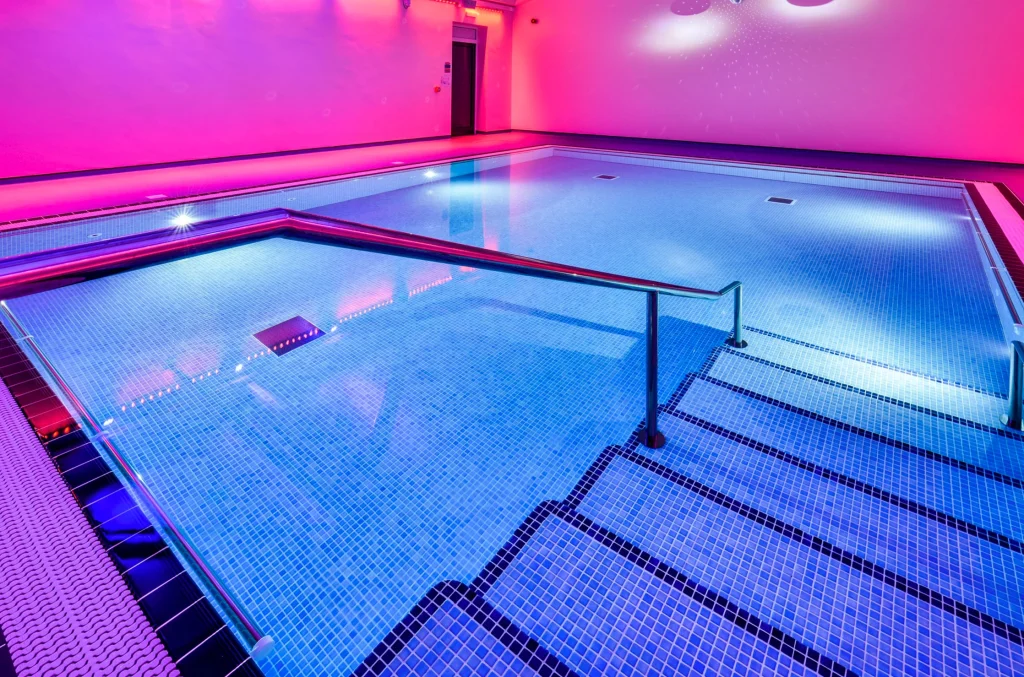 Modern indoor swimming pool with neon pink and blue lighting