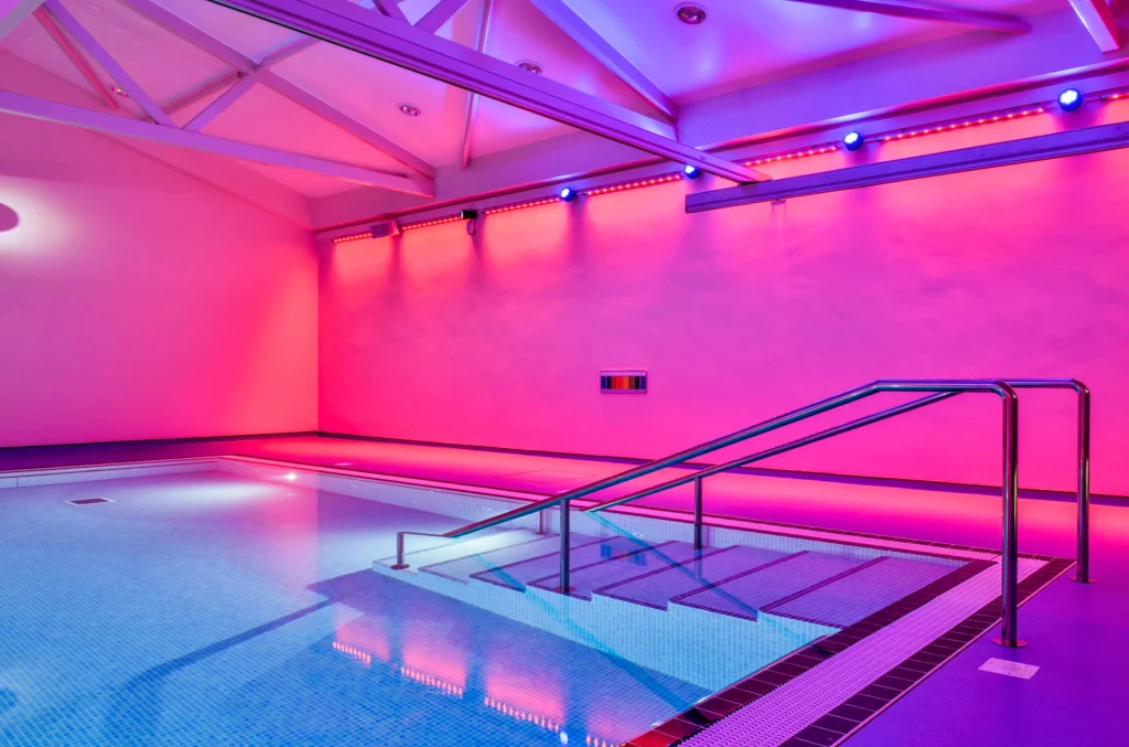 Modern indoor swimming pool with vibrant neon pink and purple lighting