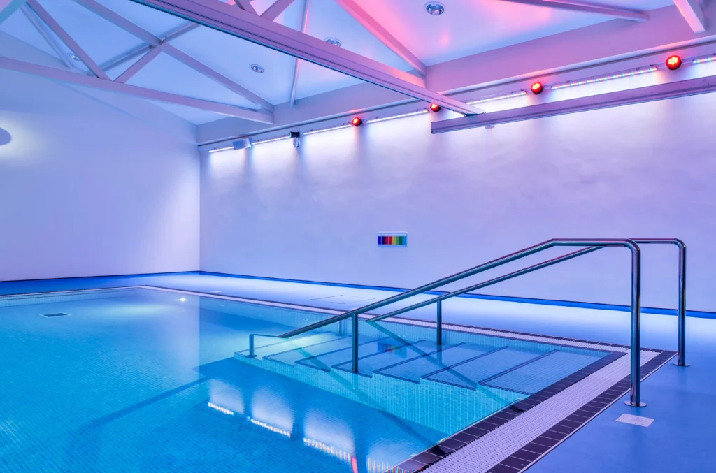 Modern indoor swimming pool with blue water and pink lighting